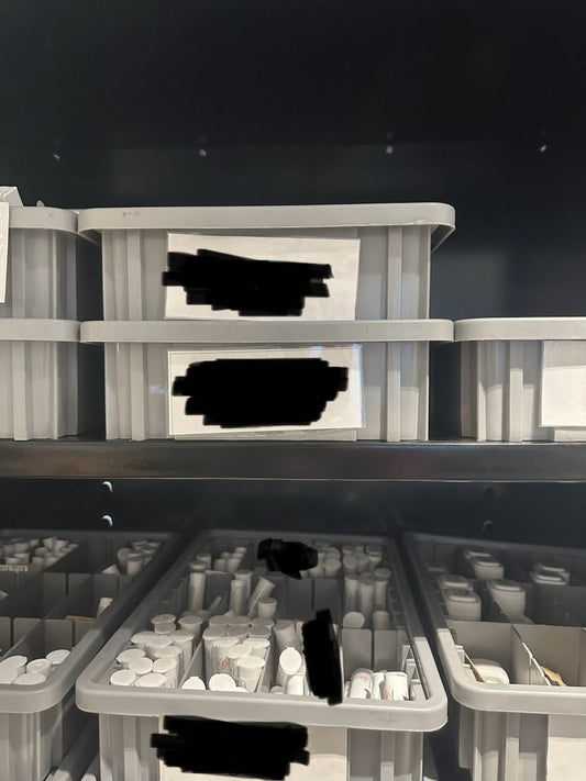 Gray divider boxes storing pharmacy products on dark shelving 4